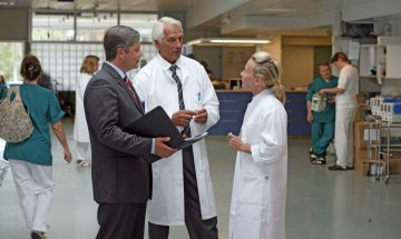 kolme henkilöä keskustelemassa sairaalaympäristössä